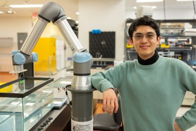 Thomas Lu stands next to a robotic arm in the Vlaisavljevich Research Lab. Photo by Ben Murphy for Virginia Tech.