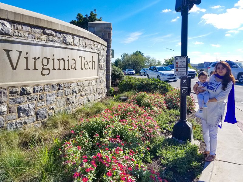 Neelma Bhatti and her child standing next to a Virginia Tech sign