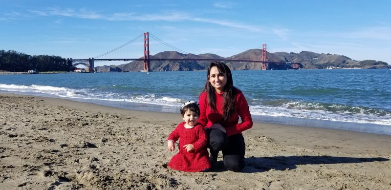 Neelma Bhatti and her child on a beach with the Golden Gate Bridge in the background